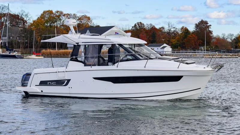 4803jg Yacht Photos Pics 2021 Jeanneau NC 895 boat cruising on a calm lake with autumn trees in the background.