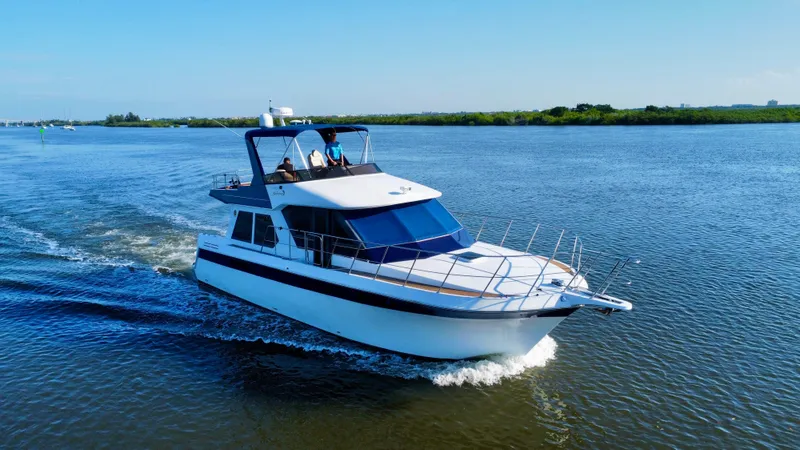 Andiamo Yacht Photos Pics 1998 Navigator Pilothouse yacht cruising on a serene river under a clear blue sky.