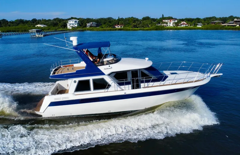 Andiamo Yacht Photos Pics 1998 Navigator Pilothouse yacht cruising on a serene lake with lush greenery.