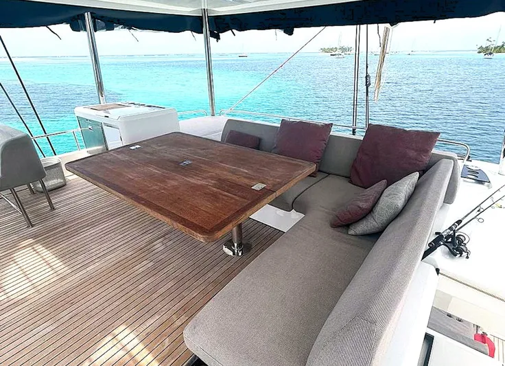 Elora Yacht Photos Pics Luxurious Lagoon 55 yacht deck with seating, wooden table, and ocean view, 2023 model.