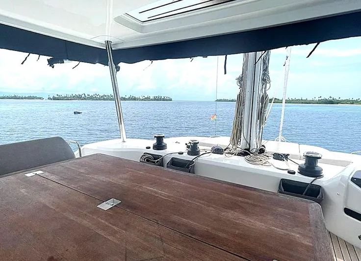 Elora Yacht Photos Pics 2023 Lagoon 55 yacht deck with ocean view and wooden table.