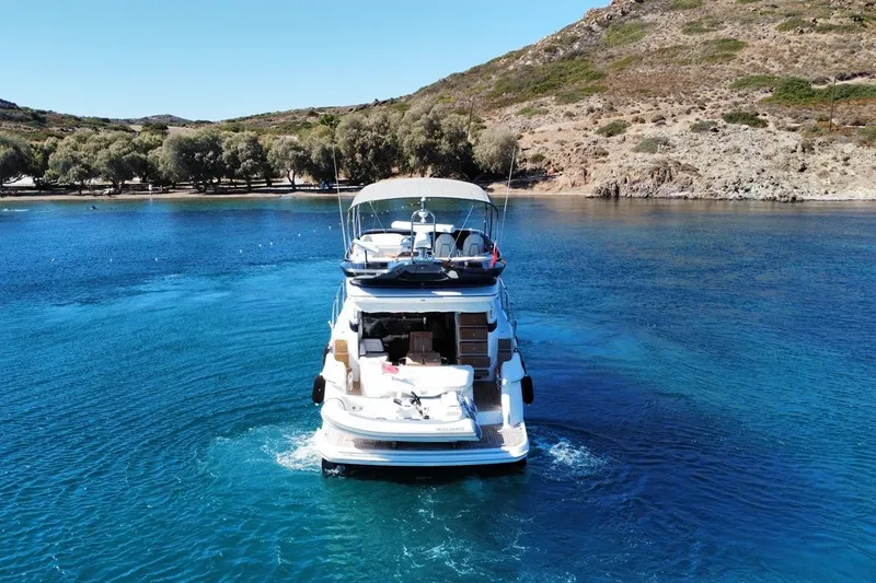 Yacht Photos Pics 2023 Princess F45 yacht cruising in clear blue waters near a rocky coastline.