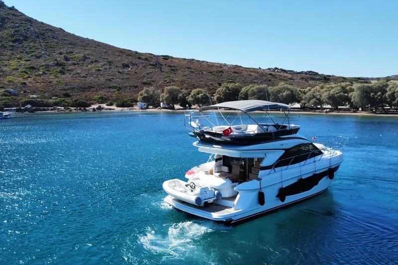  Yacht Photos Pics 2023 Princess F45 yacht cruising in clear blue waters near a scenic coastline.