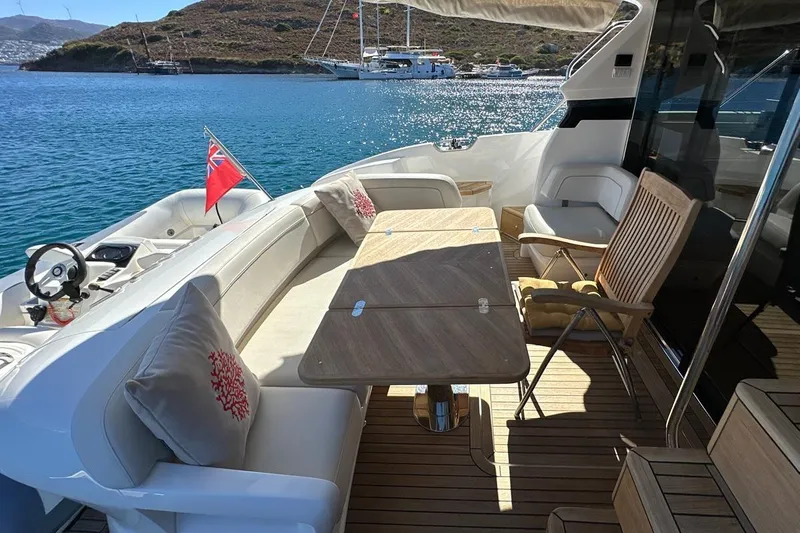  Yacht Photos Pics Luxurious 2023 Princess F45 yacht deck with seating and table, overlooking serene blue waters.