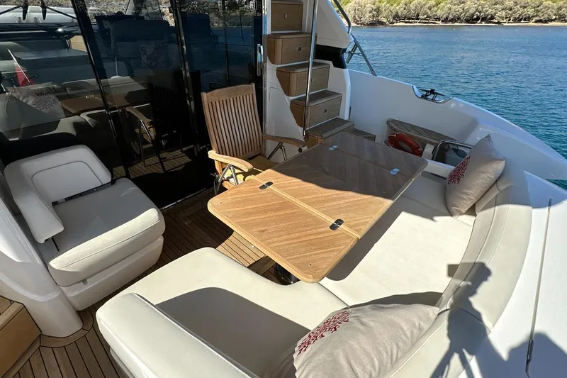  Yacht Photos Pics Luxurious 2023 Princess F45 yacht deck with seating and table, overlooking serene water.