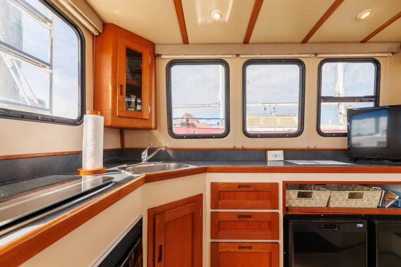  Yacht Photos Pics Interior of 2000 Nordic Tug 32, featuring kitchen area with wooden cabinetry and windows.