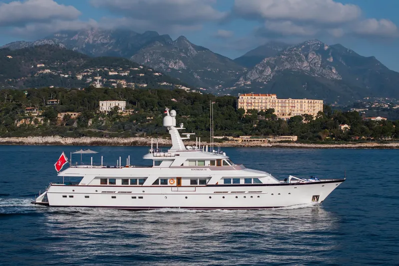 Synthesis 66 Yacht Photos Pics Luxurious 1982 Feadship yacht cruising near scenic coastline with mountains in the background.