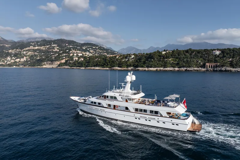 Synthesis 66 Yacht Photos Pics Luxurious 1982 Feadship yacht cruising near scenic coastline under blue sky.
