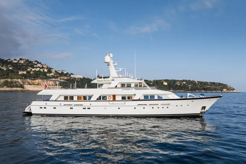 Synthesis 66 Yacht Photos Pics Luxurious 1982 Feadship yacht cruising on calm waters near a scenic coastline.