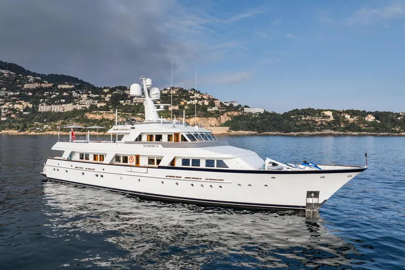 Synthesis 66 Yacht Photos Pics Luxurious 1982 Feadship yacht cruising on calm waters with scenic coastal backdrop.