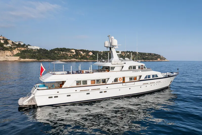 Synthesis 66 Yacht Photos Pics Luxury 1982 Feadship yacht cruising on calm waters near scenic coastline.