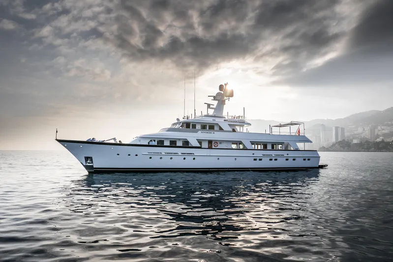 Synthesis 66 Yacht Photos Pics 1982 Feadship yacht on calm water under dramatic cloudy sky.