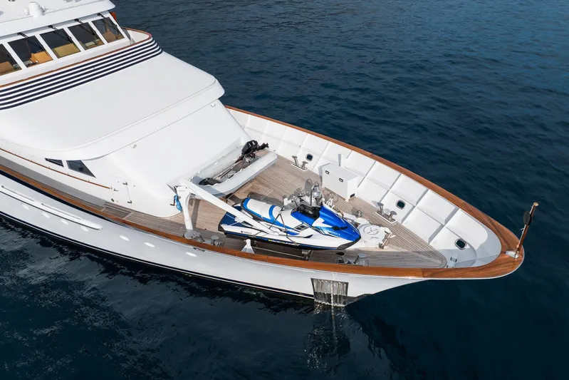 Synthesis 66 Yacht Photos Pics Luxurious 1982 Feadship yacht with jet ski on deck, cruising in clear blue waters.