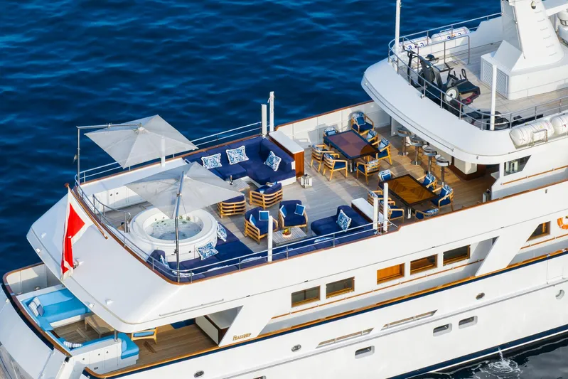 Synthesis 66 Yacht Photos Pics Luxurious 1982 Feadship yacht deck with seating, dining area, and jacuzzi on the ocean.