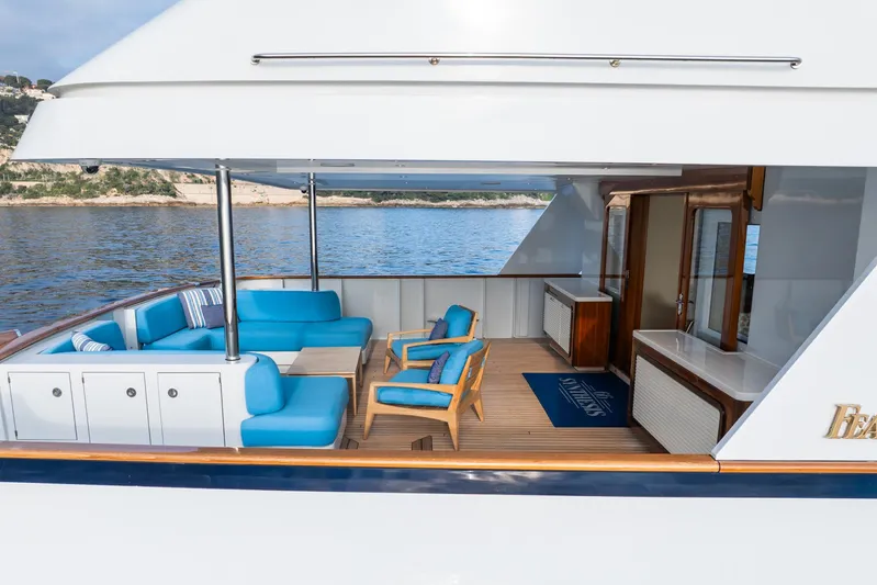 Synthesis 66 Yacht Photos Pics Luxurious 1982 Feadship yacht deck with blue seating, wooden flooring, and ocean view.