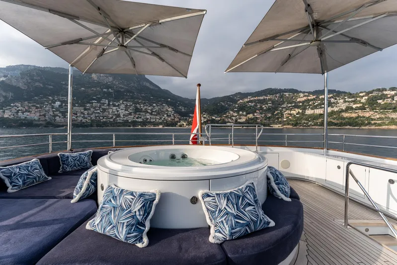 Synthesis 66 Yacht Photos Pics Luxurious 1982 Feadship yacht deck with jacuzzi, cushions, and umbrellas, overlooking scenic coastal view.
