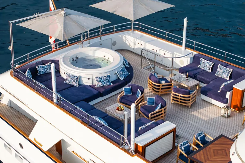 Synthesis 66 Yacht Photos Pics Luxurious 1982 Feadship yacht deck with jacuzzi, seating, and umbrellas on calm water.
