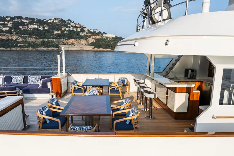 Synthesis 66 Yacht Photos Pics Luxurious 1982 Feadship yacht deck with elegant seating, bar, and scenic coastal view.