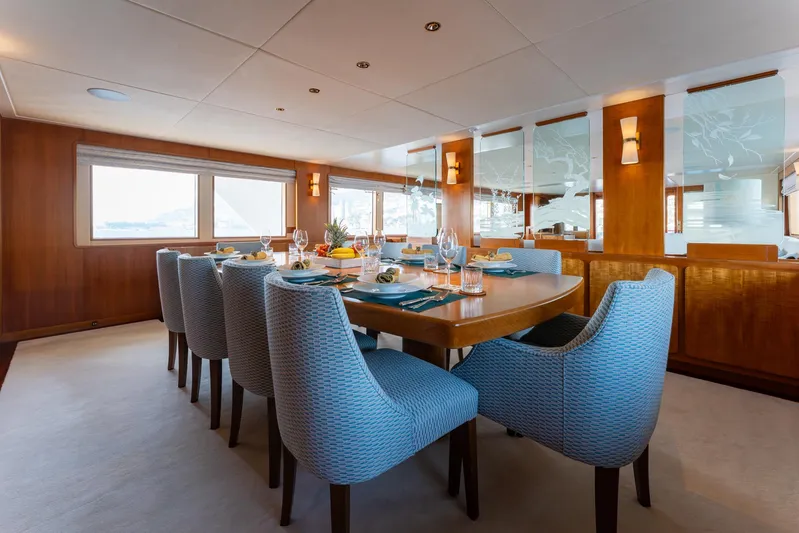 Synthesis 66 Yacht Photos Pics Luxurious dining area on 1982 Feadship yacht with elegant table setting and plush chairs.