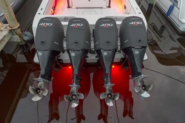  Yacht Photos Pics Four powerful outboard engines on a 2020 Contender 44 ST boat, docked with red lighting.