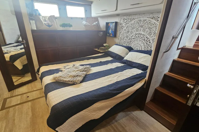 Kokomo Yacht Photos Pics Luxurious bedroom interior of 1990 Hatteras 67 Cockpit Motor Yacht with striped bedding.