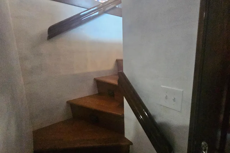 Kokomo Yacht Photos Pics Wooden staircase inside 1990 Hatteras 67 Cockpit Motor Yacht, featuring polished handrails.