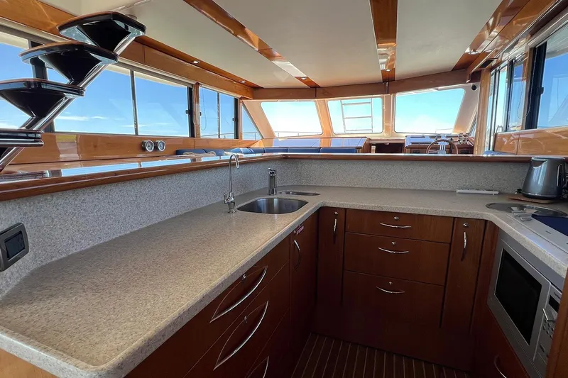 Kahala Yacht Photos Pics Luxurious kitchen interior of 2005 Maritimo M60 yacht with modern amenities and wooden finishes.