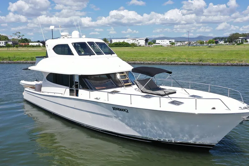 Kahala Yacht Photos Pics 2005 Maritimo M60 yacht cruising on a sunny day, with lush green shoreline in the background.