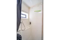 Compact shower area in a 2016 Leopard 40 catamaran, featuring a window and modern fixtures.