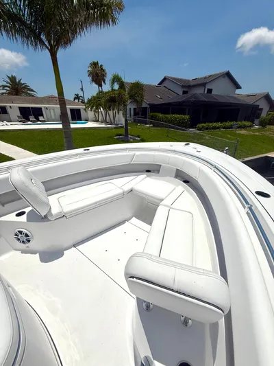  Yacht Photos Pics 2024 Sportsman 322 Open boat with white seating, docked near modern homes and palm trees.