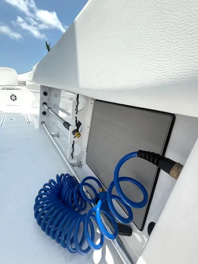  Yacht Photos Pics 2024 Sportsman 322 Open boat deck with blue coiled hose and storage compartment.