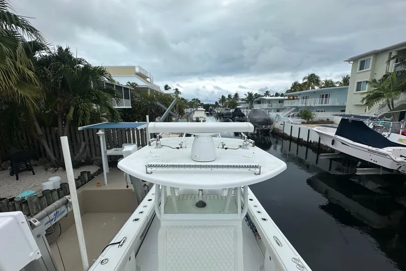 Yacht Photos Pics 2012 Yellowfin 32 Offshore boat docked in a residential canal, surrounded by palm trees and houses.
