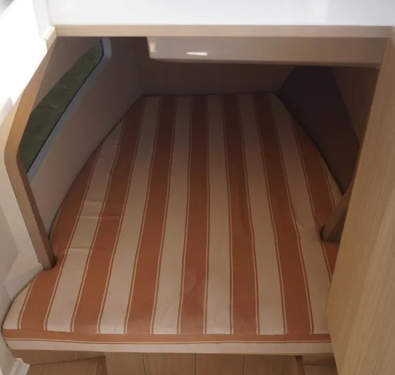 Sea)3 Yacht Photos Pics 2022 Aquila 32 Sport cabin with striped mattress and wooden interior.
