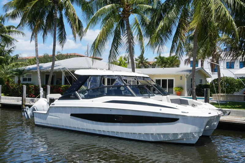 Sea)3 Yacht Photos Pics Aquila 32 Sport 2022 boat docked by palm trees and waterfront homes.
