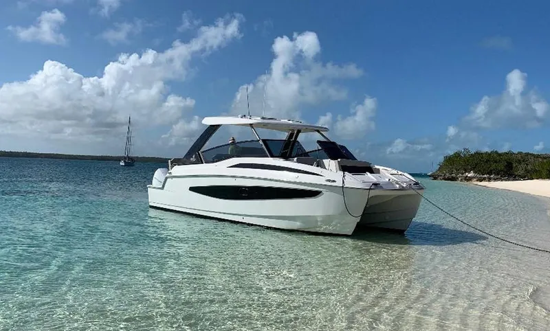 Sea)3 Yacht Photos Pics Aquila 32 Sport 2022 boat anchored on a clear, tropical beach.