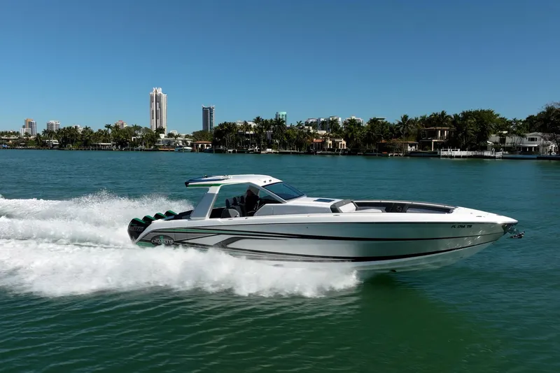  Yacht Photos Pics 2024 Cigarette 42' Auroris speedboat cruising on a sunny day near a coastal cityscape.