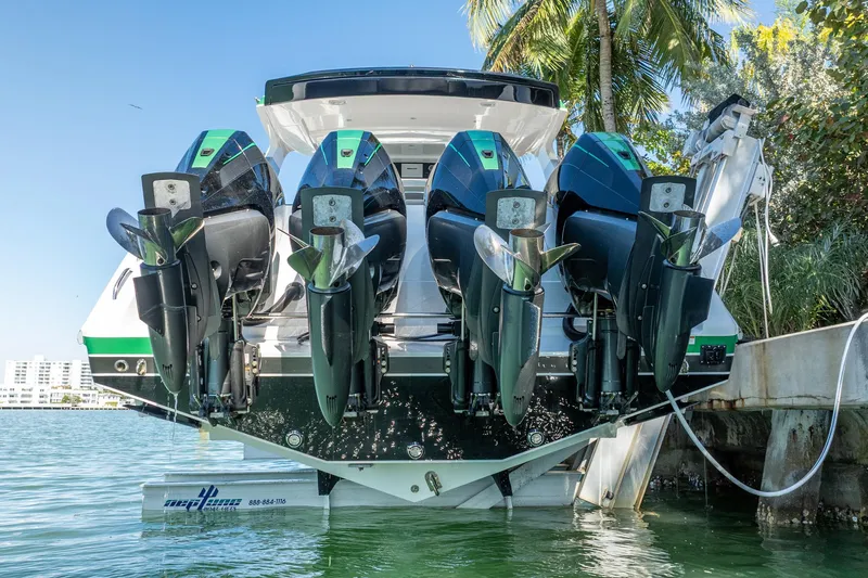  Yacht Photos Pics 2024 Cigarette 42' Auroris with powerful outboard engines docked by lush greenery.