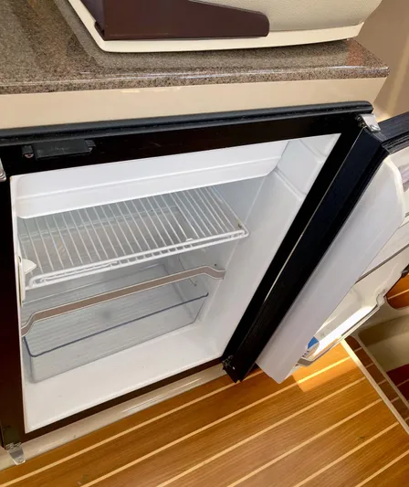 Seaburd Yacht Photos Pics Open refrigerator inside 2018 Ranger Tugs R-29 S boat, showing empty shelves and wooden flooring.