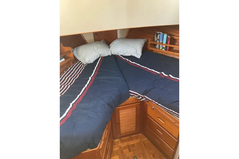 Burnin Daylight Yacht Photos Pics Cozy cabin bedroom in 1983 Grand Banks 42 Classic yacht with striped bedding and wooden storage.