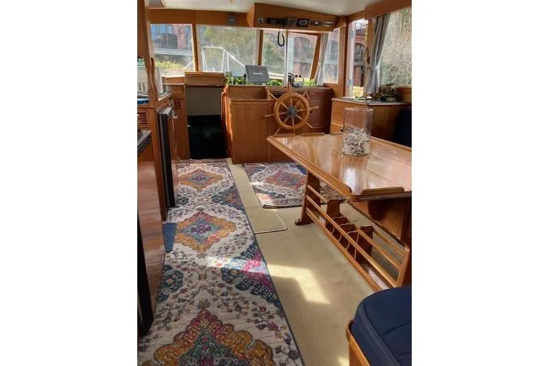 Burnin Daylight Yacht Photos Pics 1983 Grand Banks 42 Classic interior with wooden helm, colorful rugs, and dining table.