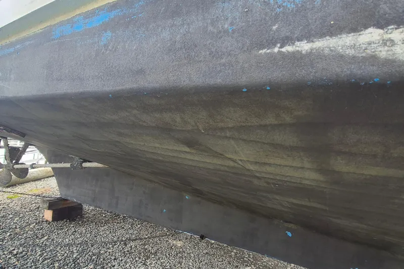 Burnin Daylight Yacht Photos Pics 1983 Grand Banks 42 Classic boat hull on gravel, showing wear and blue paint remnants.