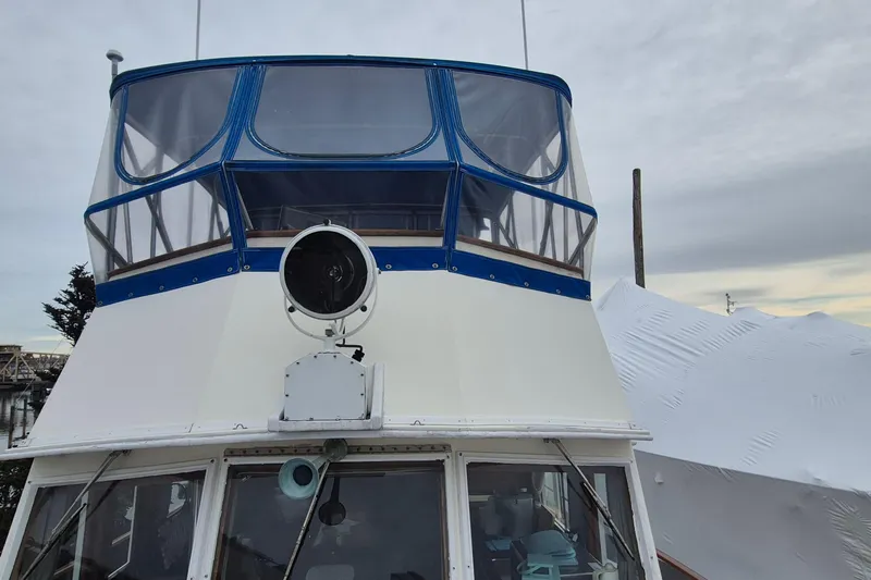 Burnin Daylight Yacht Photos Pics 1983 Grand Banks 42 Classic yacht with blue canopy and spotlight, docked under cloudy skies.