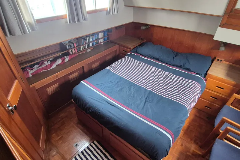 Burnin Daylight Yacht Photos Pics Cozy bedroom in 1983 Grand Banks 42 Classic yacht with wood paneling and striped bedding.