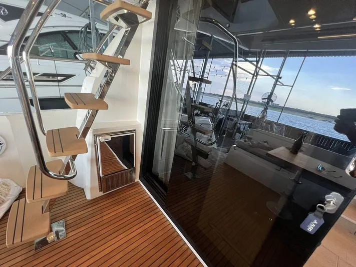 Velkommen Yacht Photos Pics Prestige 460F 2022 yacht interior with wooden stairs and glass doors, overlooking the water.