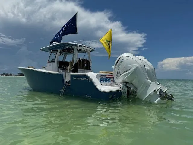  Yacht Photos Pics 2023 Sportsman 322 Open boat with flags, anchored in clear water under a blue sky.