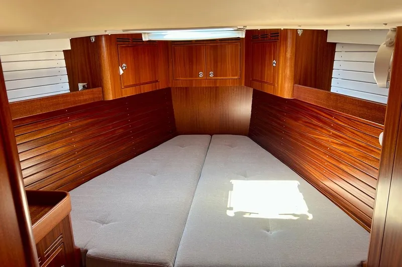 Magic I Yacht Photos Pics Luxurious 2021 Hallberg-Rassy 44 yacht cabin with elegant wood paneling and cozy bedding.