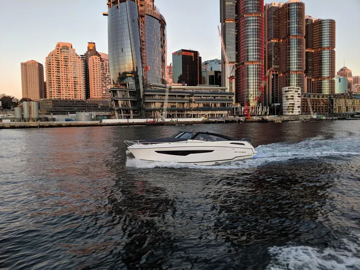  Yacht Photos Pics 2024 Skamander 850 Voyager cruising near modern city skyline at sunset.