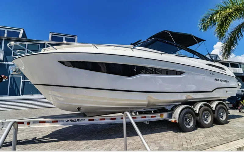  Yacht Photos Pics 2024 Skamander 850 Voyager boat on trailer, sleek design, sunny day, palm tree background.