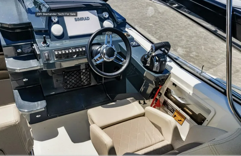 Yacht Photos Pics 2024 Skamander 850 Voyager yacht cockpit with steering wheel and control panel.