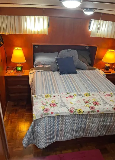  Yacht Photos Pics Cozy bedroom in 1987 DeFever Tri-Cabin yacht with warm lighting and floral bedding.